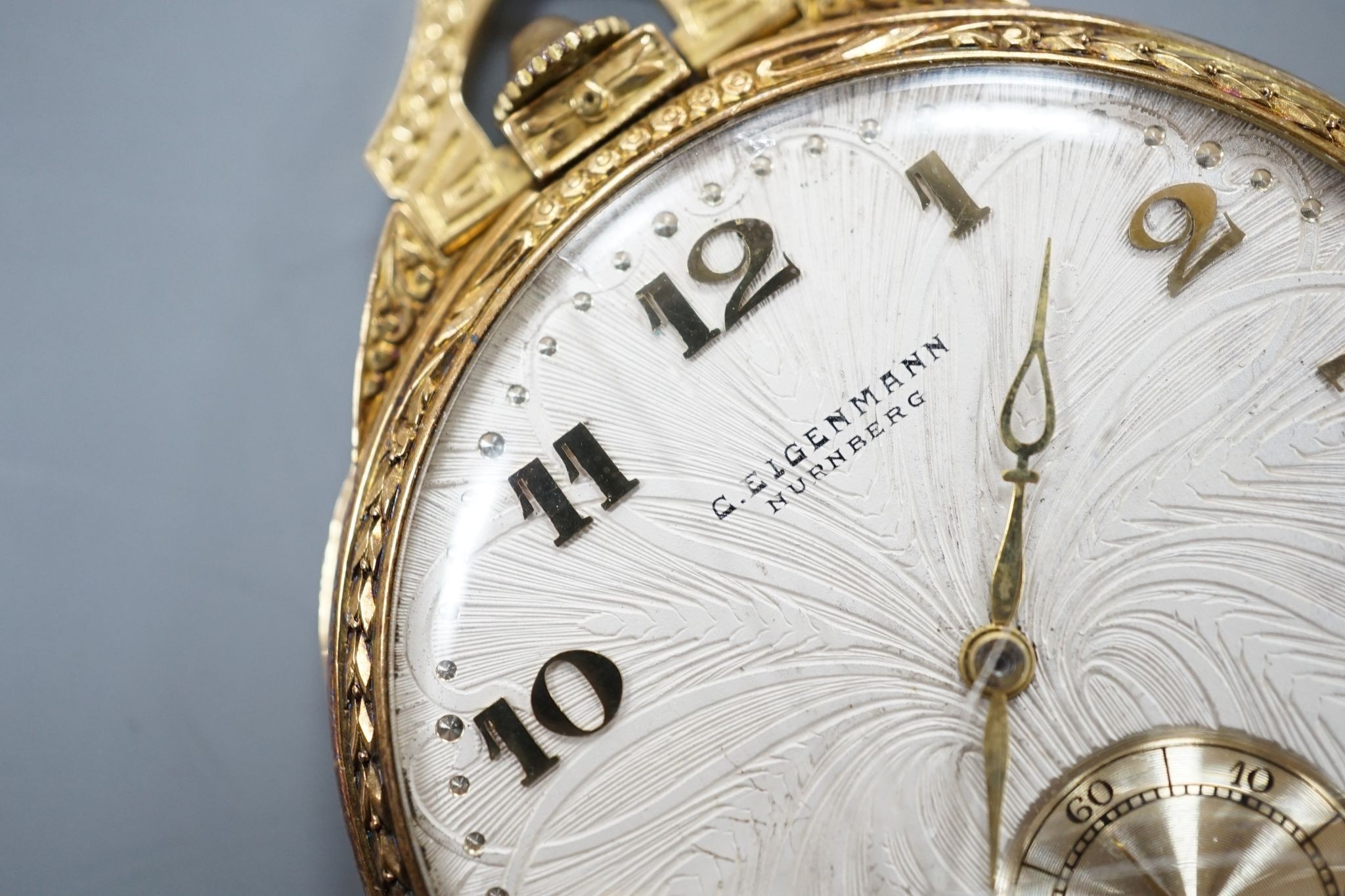 A continental engine turned 750 yellow metal open face dress pocket watch, retailed by Eigenmann, Nuremburg